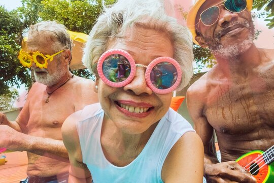 Closeup of diverse senior adults sitting by the pool enjoying summer together