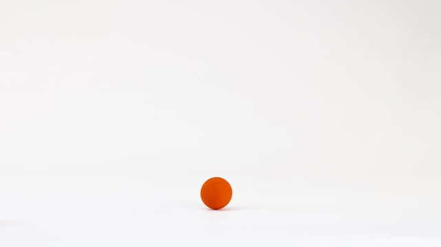 Two Orange Spheres Rolling and Bouncing Across a White Background