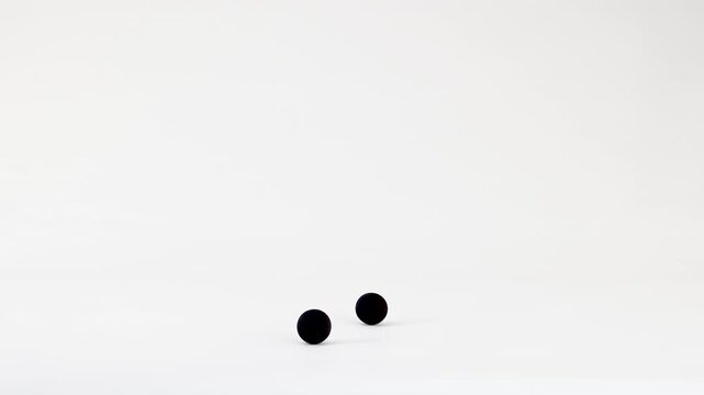 Minimalist Animation of Black Spheres Falling and Bouncing on White Background