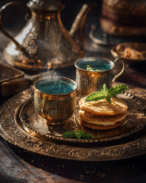 Steaming mint tea and chebakia served on ornate brass tray with traditional cups and cookies, warm aromatic setting and elegant metalwork