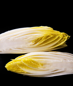 Hald-Sliced Fresh Belgian Endive Witloof White Chicory Vegetable on Black Background