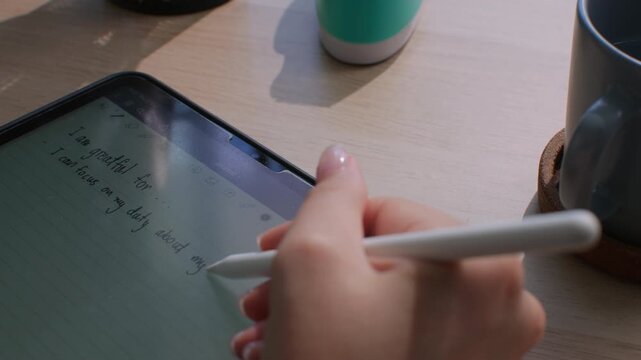 Gen Z woman uses digital tablet and stylus to journal her thoughts, reflect on goals, and practice gratitude, blending mindfulness with technology while embracing eco-conscious lifestyle