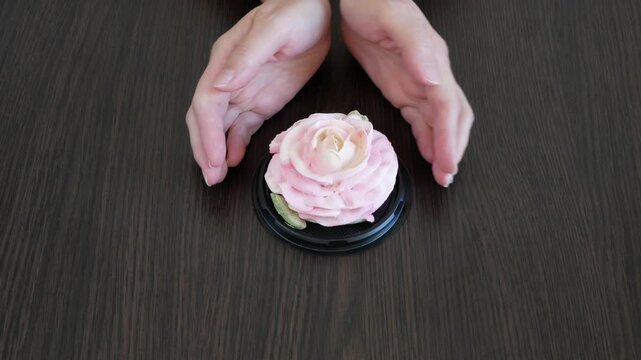 Hands draw a heart on the table around a marshmallow rose flower. Holiday gift. Love.