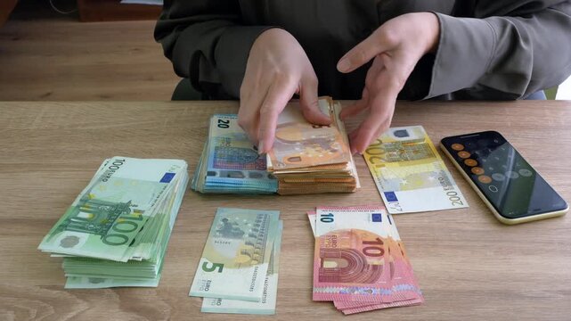 hand counting big stack of euro money on wooden background. money cash, closeup