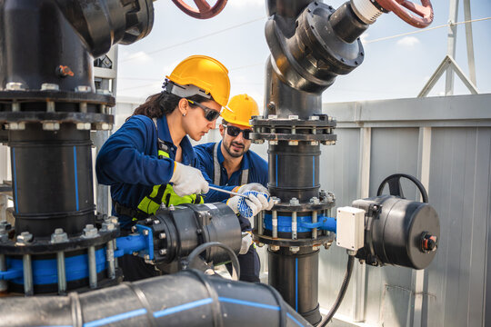Professional maintenance team working with a wrench to fix heavy duty water or gas pipes, Technicians in safety gear performing routine inspection and maintenance on a mechanical plumbing system