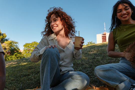 Smiling young women enjoying picnic in park on sunny day