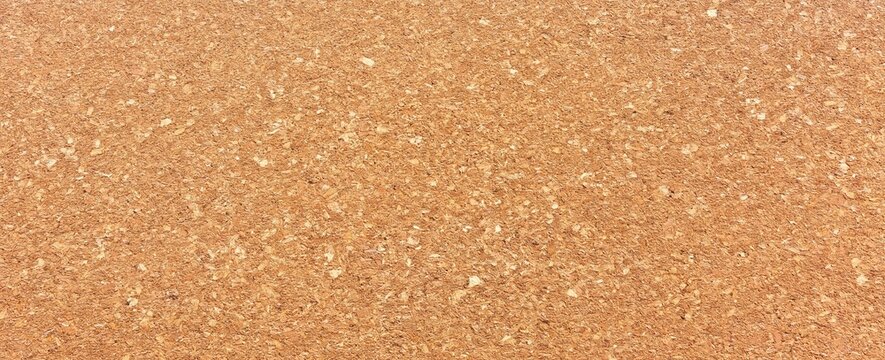 Close-up image of corkboard texture showing natural, rough surface with various shades of brown and irregular patterns.