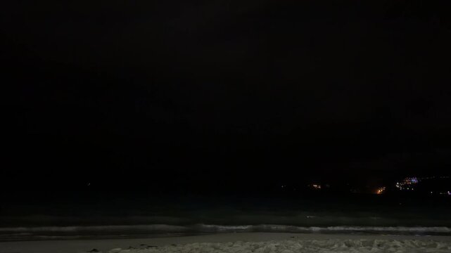 Mysterious lightning glow inside heavy storm clouds over the Andaman Sea. Dramatic night seascape at Phuket beach, Thailand, moody tropical nature phenomenon, majestic monsoon atmosphere, authentic.
