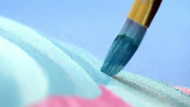 Extreme close up of paintbrush applying blue paint on canvas texture