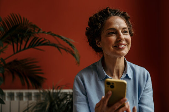 Woman smiling while using phone and looking away
