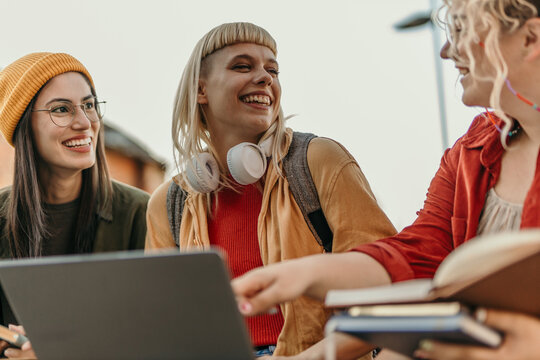 Diverse students laughing while studying together outdoors