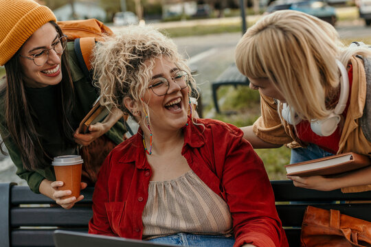 Diverse university students laughing, studying together on campus