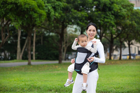 Mother carrying baby in park enjoying peaceful outdoor moment