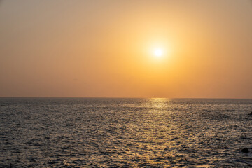 Obraz premium Sunset at the sea. The sun is setting in golden haze over the calm sea.