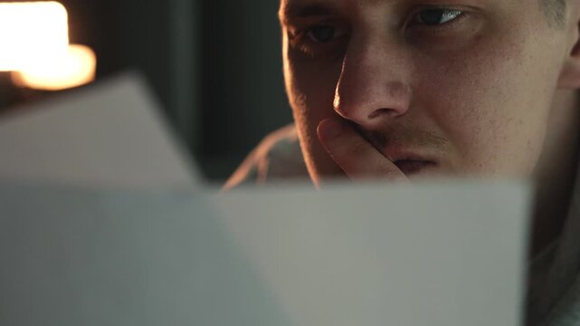 Close-up of white documents being read in dark room. Important papers, notes, script, or information review. Concept of analysis, journalism, investigation, reading documents, and decision making with