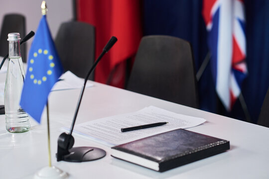 Close up of conference table displaying microphones, documents, EU flag, British flag, preparing diplomatic negotiation or policy briefing. Ideal for government, trade