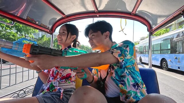 Young Asian Couple Celebrating Songkran Festival with Water Guns in Tuk Tuk