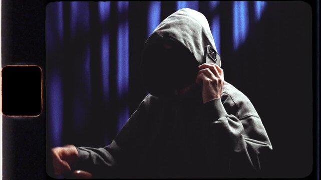 Anonymous hooded person receiving a phone call