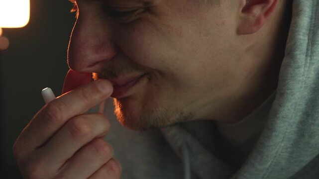 Close-up of a person treating blocked nose with nasal spray at night. Focus on respiratory health, allergy or cold symptoms, sinus relief, and medication use in a home environment