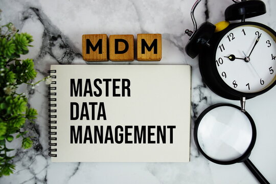MDM Master Data Management text with alarm clock and magnifying glass on marble background