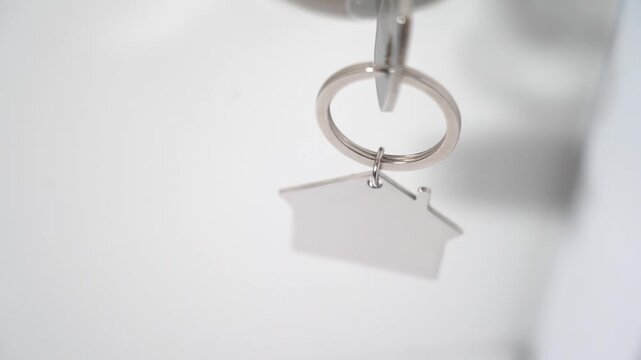 A keychain with a house and a ring on the key inserted in the front door is the concept of your home for the purchase of a new apartment at home. High quality FullHD footage