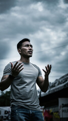 Naklejka premium A man with short hair gestures outdoors against a cloudy sky.