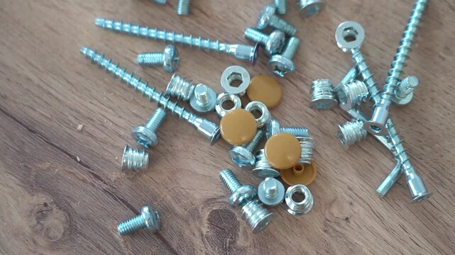 Bolts nuts plugs for furniture assembly on a wooden background close-up. High quality FullHD footage