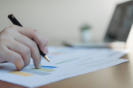 Businessperson analyzing corporate profit statistic chart pen desk digital transition financial auditing workflow quarterly financial review modern office workspace.