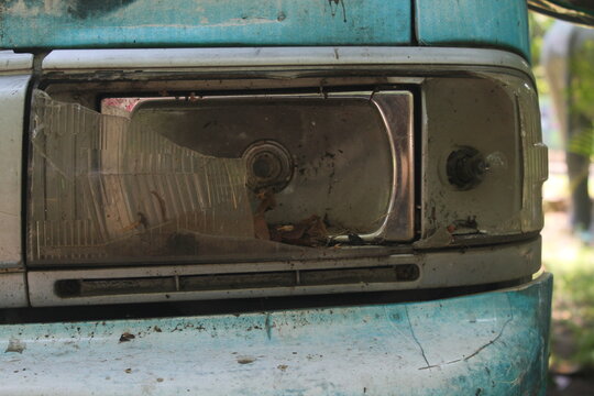 Close-up of a Broken Headlight on an Abandoned Blue and White Car