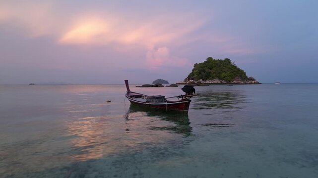 Koh Lipe, Thailand: Cinematic aerial drone footage of long tail boat at a beach the Koh Lipe island in the Andaman sea in southern Thailand at dramatic sunset. Shot with a slow motion effect