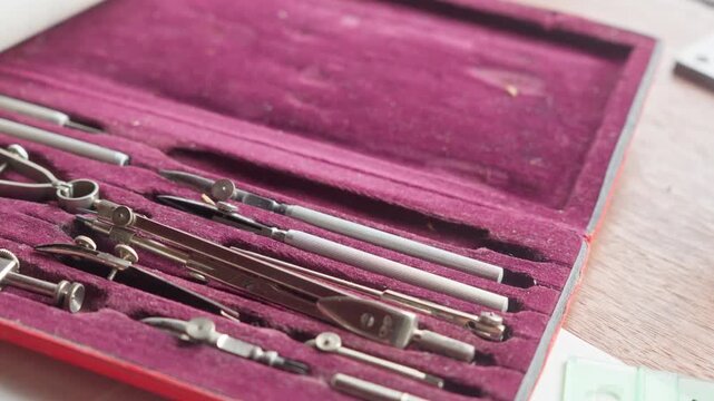 Close POV shot of a hand selecting a metal instrument, emphasizing tactile precision and careful tool choice in design tasks