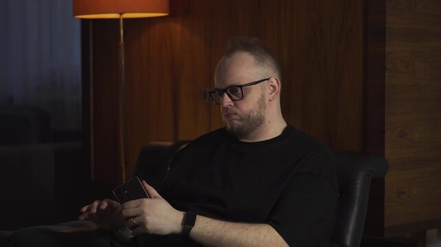 Frustrated man sitting indoors ignores or declines a phone call, showing annoyance, conflict, and communication breakdown.