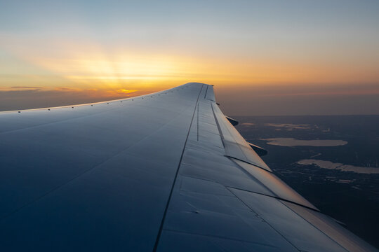 A spectacular sunset with amazing sunbeams and colors on the horizon far away seen over the wing of a flying plane on its way to Cape town in South Africa