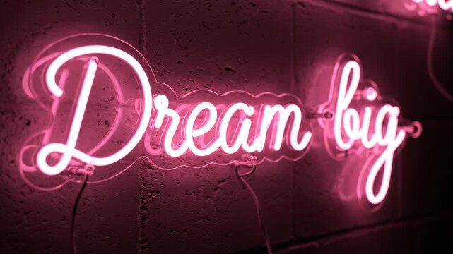 Inspiring pink neon sign with the phrase "Dream Big" glowing on a textured wall