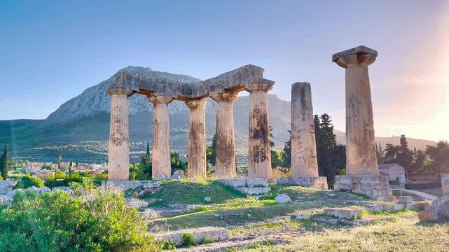 Temple of Apollo in Ancient Corinth with Acrocorinth mountain in background, Greece. Archaic Doric columns and archaeological ruins at sunset. Classical Greek heritage site.
