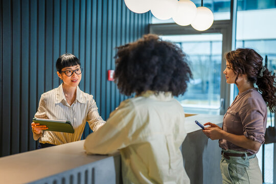 Receptionist assisting customer checking in using tablet