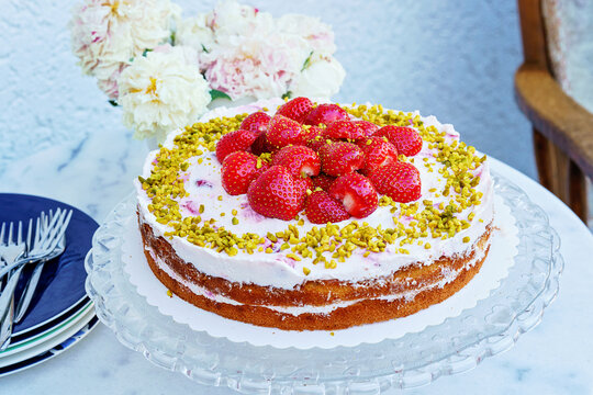 Freshly baked traditional Swedish strawberry cake, also known as Midsommar cake. Summer dessert with cream and berries. Real life, real people, homemade festive treat.