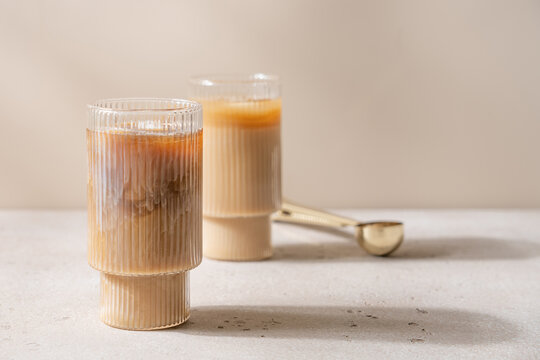 Refreshing Iced Cappuccino with Creamy Milk Foam in Clear Glass on Soft Beige Background, Minimalist Aesthetic, Natural Light, Copy Space for Text, Summer Cold Coffee Drink Concept
