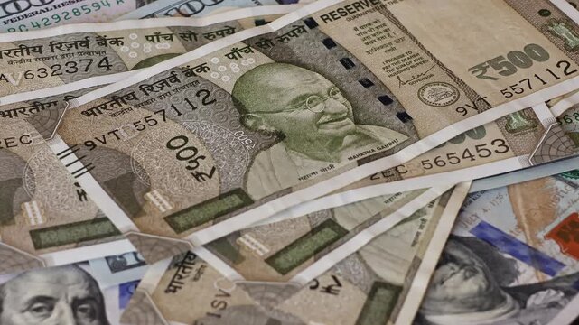 500 Indian rupee notes falling on one hundred US dollar banknotes. Concept of exchange rate, global finance, investment and international economy. Real time motion footage.