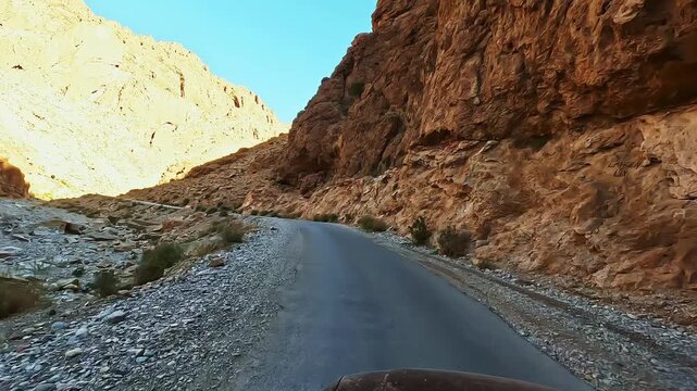 Driving through the stunning todra gorge canyon on a scenic mountain road in the high atlas, morocco, at sunset