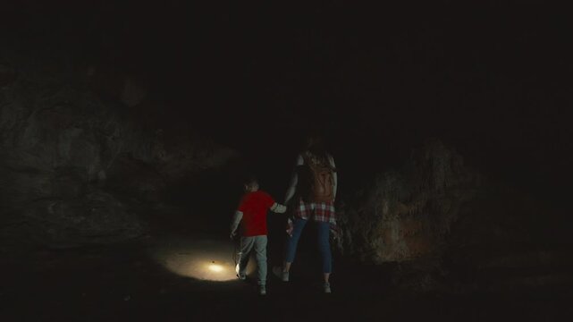 Mother and son exploring a dark cave together