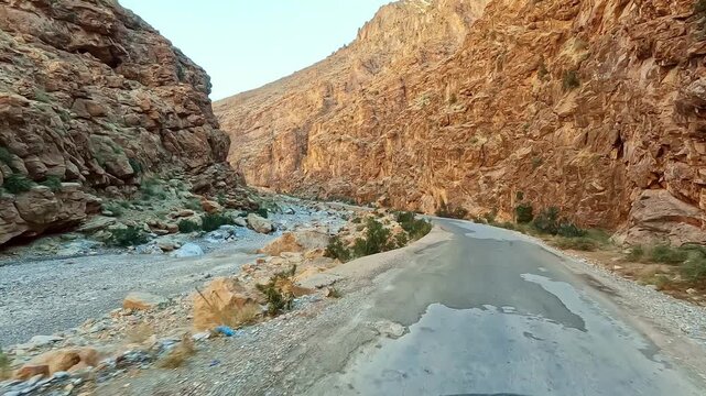 Driving through todra gorge canyon on a narrow road in the atlas mountains of morocco, a stunning natural landscape pov