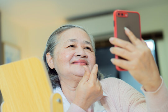 Asian senior woman using smartphone for video call or selfie with happy mood