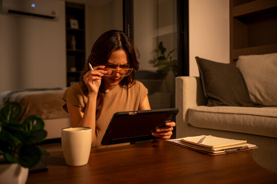 Woman squinting eyes reading tablet in low light