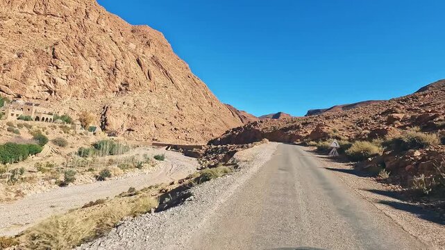 Driving through the scenic mountain road of todra gorge in morocco on a beautiful sunny day with a clear blue sky