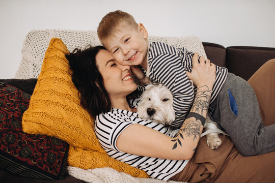 Happy family with child and pet dog bonding on sofa