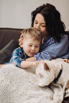 Mother kissing son and petting dog at home