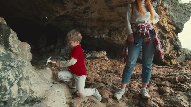 Young boy geologist exploring rocks with hammer