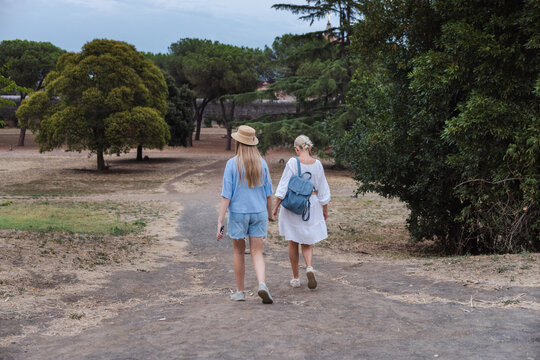Mother and teenage daughter walking together along path in Parco degli Acquedotti Rome enjoying travel moment in Italy among trees and greenery