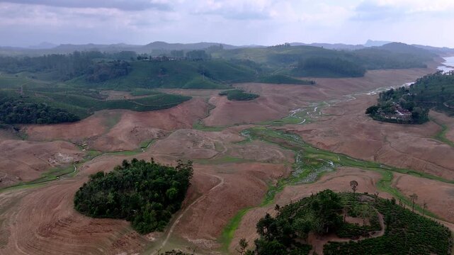 Drone shot capturing landscapes near Sholayar Reservoir featuring serpentine roads, green tea estates, barren patches, and layered hills creating a dramatic and diverse natural scene.